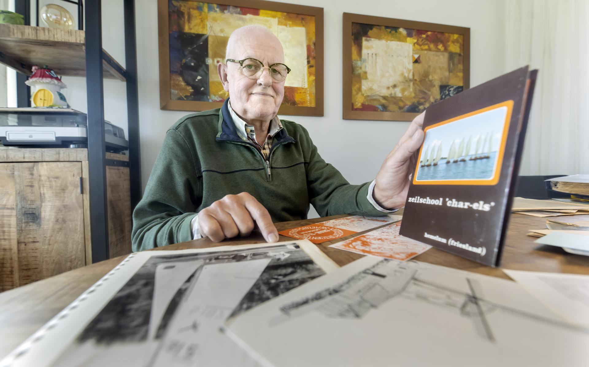 Charles Laponder met een boek van zijn vroegere zeilschool Char-Els uit Hemelum en foto's van polyvalken.