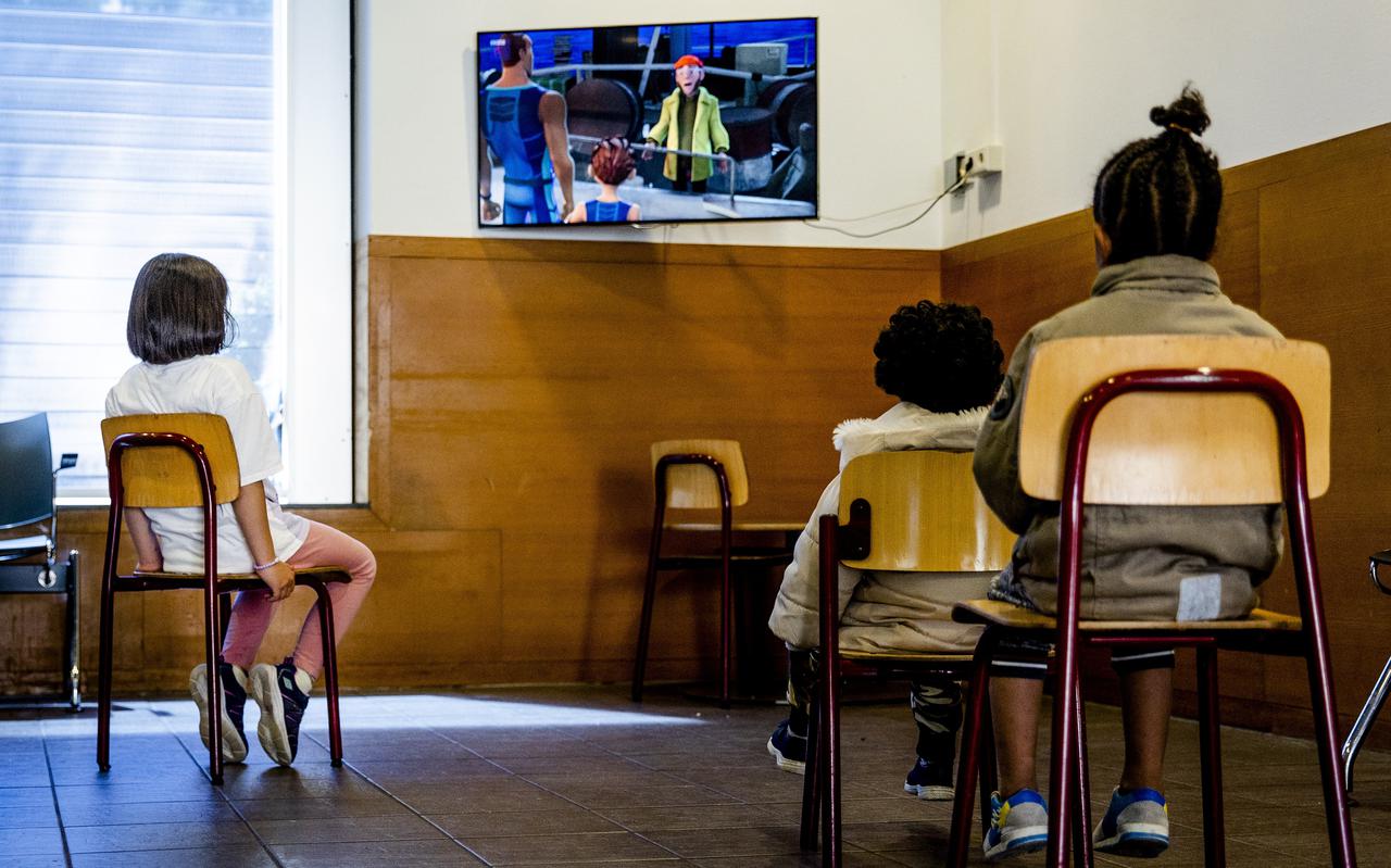 Kinderen kijken tv in een wachtruimte in het aanmeldcentrum voor asielzoekers in Ter Apel.