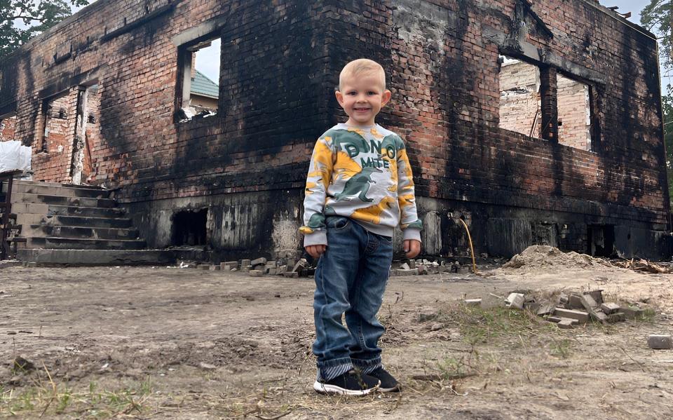De zoon van Roman Golovanov voor hun verwoeste huis in Irpin. 