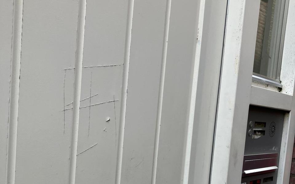 Een gekrast hakenkruis op de deur in de Schoolsteeg.
