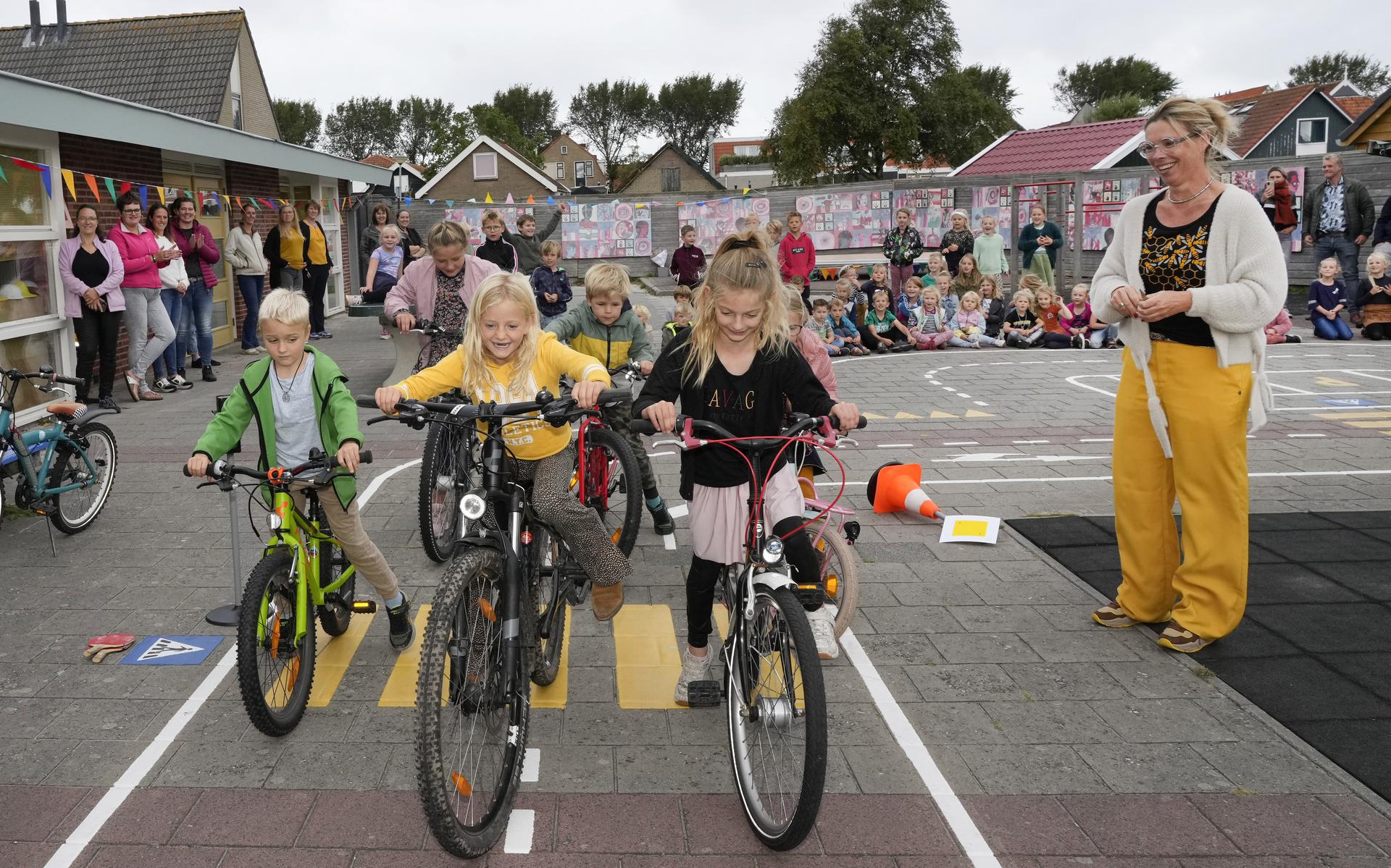 Esmé Bijlsma, directeur van Hunnighouwersgat, kijkt vrolijk toe terwijl de kinderen het eerste rondje over het verkeersplein fietsen.