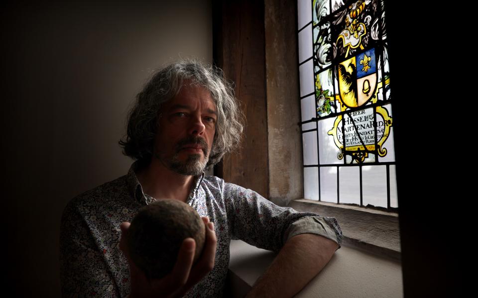 Conservator Josse Pietersma van Museum Martena in Franeker toont een kanonskogel die mogelijk tijdens het 'Beleg van Franeker' werd afgeschoten. Rechts naast hem het familiewapen van edelman Hessel van Martena: ,,De grutste lânferrieder fan Fryslân.’’
