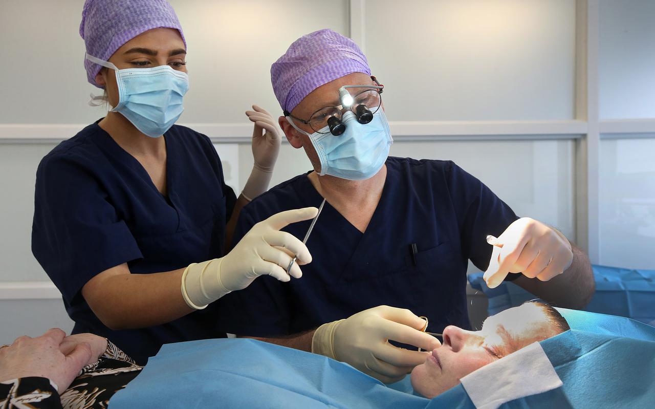 Plastisch chirurg Eddy Verschuur (rechts) verwijdert vetophopingen boven de oogleden bij een 47-jarige vrouw. Links assistente Lea Berdynaj.