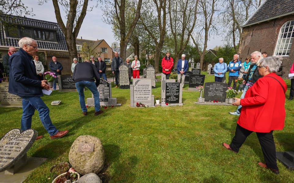 Nabestaanden plaatsen bloemen bij de graven van Geertruida Westra en Jelmer, Gerrit en Sjoerd de Jong op het kerkhof in Tirns.