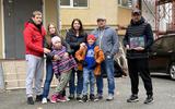 Bewoners van Ukrains'ka Street 85 bereiden zich voor op de winter. Vlnr: Dima, Irina, Arisha, Svitlana, Dima, Oleg en Nik. Op de iPad de vrouw en zoon van Nik, zij verblijven in het buitenland