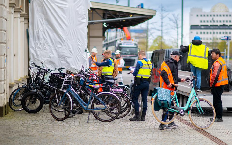Handhaving haalt fietsen voor het Leeuwarder station weg, zodat schilders het station kunnen verven. 