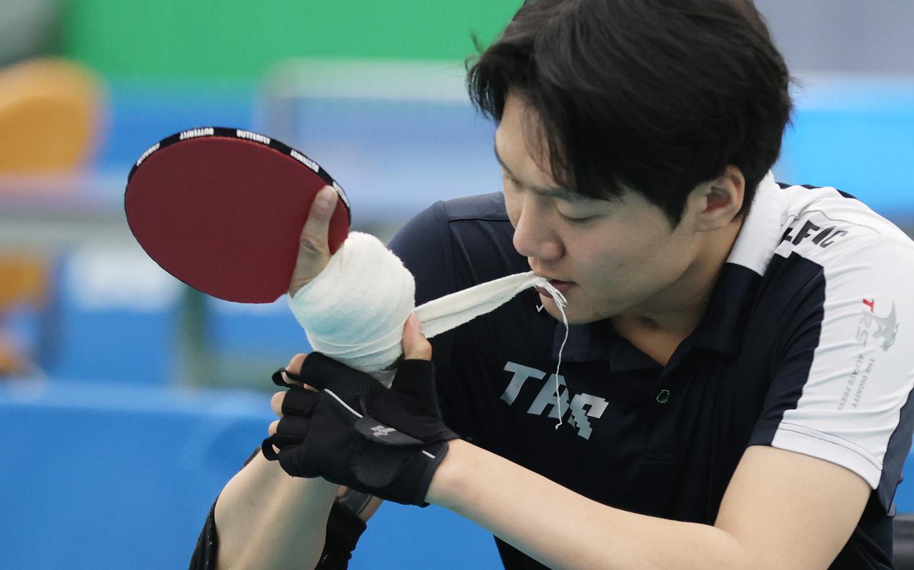 Tafeltennissppeler Kim Hyun-Wook van Zuid-Korea bindt een batje vast aan zijn hand.