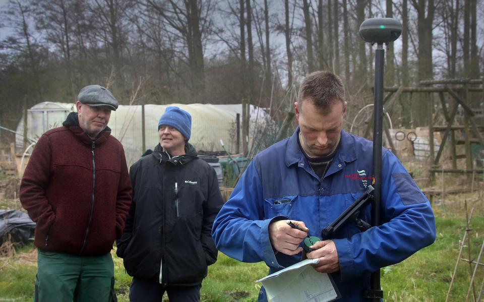 Tuinders Richard de Vries (links) en Haise van der Veen kijken toe hoe een medewerker grondmonsters neemt van hun moestuin.