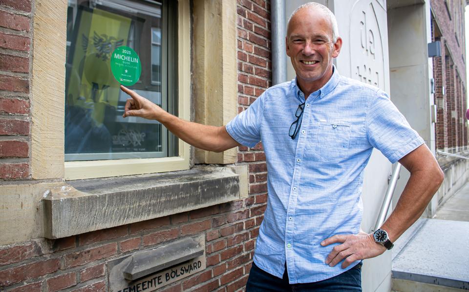 Directeur Fred Boersma wijst naar de sticker die op het raam naast de ingang aangeeft dat De Tiid een speciale vermelding heeft gekregen in de gerenommeerde Michelingids.