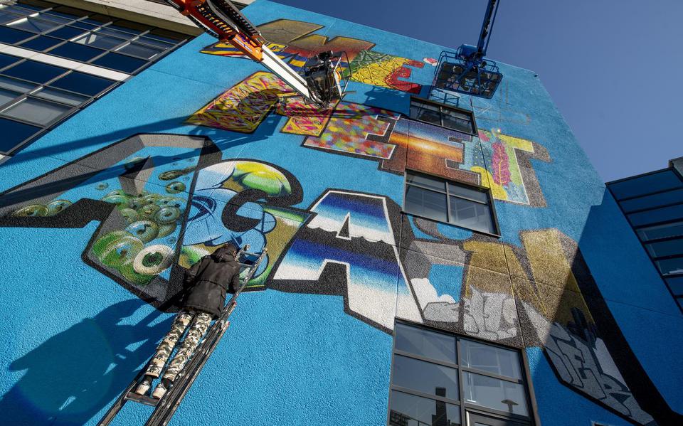 Graffitikunstenaars schilderen op het NDC-gebouw in Leeuwarden de tekst ‘Well’meet again’.