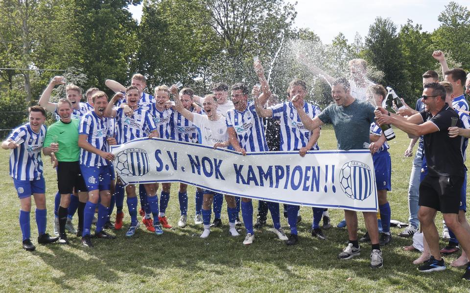 De spelers van NOK ontkurken de champagne als de titel binnen is.